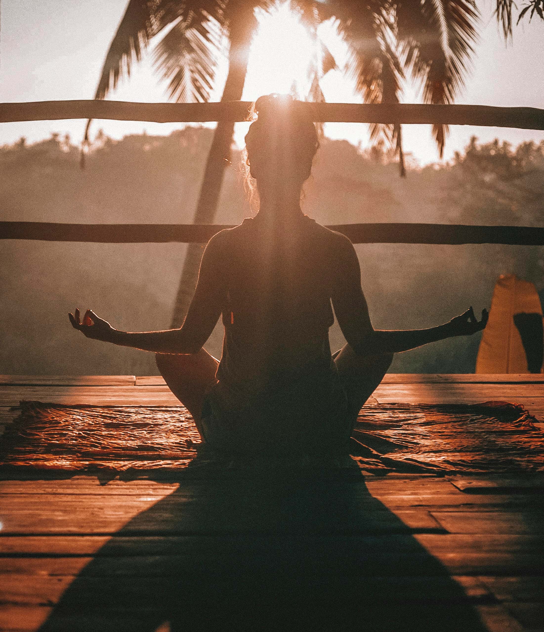 A woman meditating on a wooden floor in golden light
